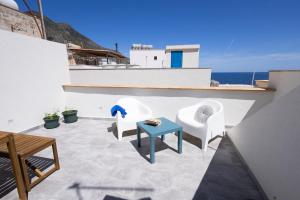 a patio with white chairs and a blue table at Montebello Room's in Marettimo