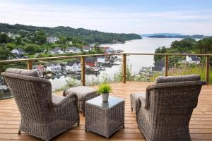 a balcony with two chairs and a table with a view of the water at Luxury Fjord Cabin with jacuzzi, boat dock & view in Sveio