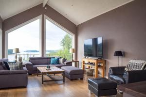 a living room filled with furniture and a large window at Luxury Fjord Cabin with jacuzzi, boat dock & view in Sveio