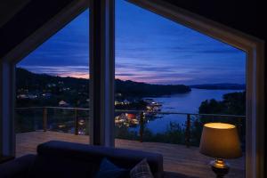 a room with a large window with a view of a lake at Luxury Fjord Cabin with jacuzzi, boat dock & view in Sveio