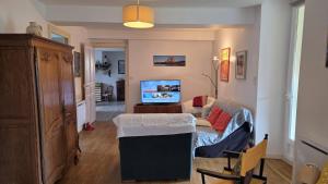 a living room with a couch and a tv in it at Gîte du moulin d'Arudy en Vallée d'Ossau in Arudy