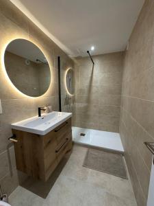 a bathroom with a sink and a shower and a mirror at Le Cocon de Milan in Valras-Plage