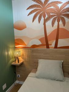 a bedroom with a mural of palm trees on the wall at Le Cocon de Milan in Valras-Plage