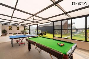a pool table in a room with windows at EKOSTAY Luxe - Black Mirror in Igatpuri