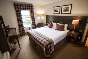 a hotel room with a large bed and a window at The Loans Inn in Troon
