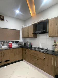 a kitchen with wooden cabinets and a stove top oven at Ranim Family Lodge - Abbottabad in Abbottabad