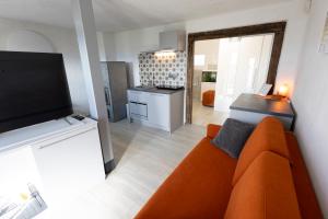a living room with an orange couch and a flat screen tv at Nogica in Otočec