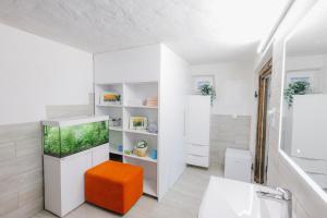 a bathroom with a fish tank and an orange stool at Nogica in Otočec +6 photos