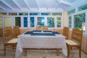 a dining room with a table and chairs and windows at Forest Rest House Gahan in Bāgi