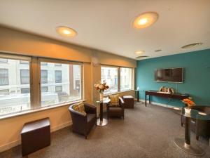 a waiting room with chairs and a table and a tv at Citrus Hotel Cheltenham by Compass Hospitality in Cheltenham