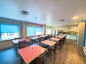 a restaurant with tables and chairs and a kitchen at Citrus Hotel Cheltenham by Compass Hospitality in Cheltenham