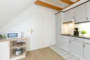 a kitchen with white cabinets and a microwave at Strandhotel Laboe Nr 35 in Laboe