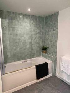a bath tub in a bathroom with green tiles at Large town centre apartment with parking in Wallingford