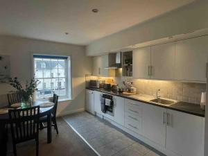a kitchen with white cabinets and a table and a window at Large town centre apartment with parking in Wallingford