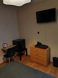 a bedroom with a bed and a dresser with a television at Notre Dame d'Orgemont - Marron 6 in Argenteuil