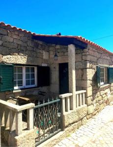 a stone house with a gate in front of it at Casinha CB in Casteição