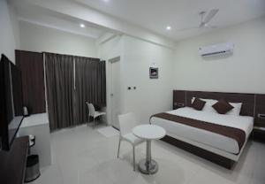 a bedroom with a bed and a table and a chair at Nandha Grande in Udumalaippettai +15 photos