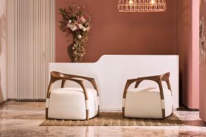 a white table with two chairs and a vase with flowers at Tzanis Resort Skyros in Skiros