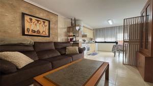 a living room with a brown couch and a kitchen at PISO AINETXA in Posada de Llanes