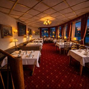 ein Restaurant mit weißen Tischen und Stühlen und Fenstern in der Unterkunft Hotel Café Post in Rüdesheim am Rhein