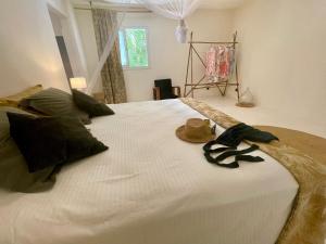 a large bed with a hat and a pair of shoes on it at Ravenala Lodge, Bungalow et Maison Ile aux Nattes in Ile aux Nattes +59 photos