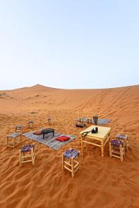 a group of tables and chairs in the desert at Erg Chebbi Nomad Camp in Merzouga