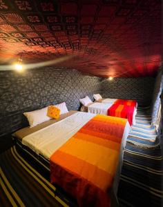 a bedroom with two beds with colorful blankets at Erg Chebbi Nomad Camp in Merzouga