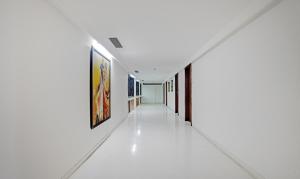 a corridor in a white room with paintings on the walls at Treebo Cherry Tree in Indore