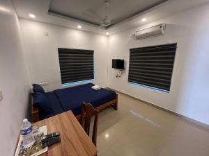 a room with a table and a blue bed and window at Confident Residency in Guruvāyūr +21 photos