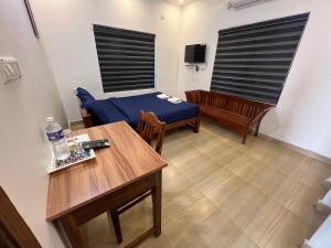 a room with a bed and a table and chairs at Confident Residency in Guruvāyūr