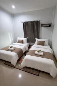 two beds in a room with white walls at Damiya Peaceful House in Ban Bo Dan