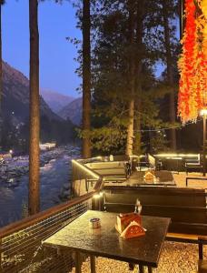 a patio with tables and a view of a river at Rivanta Resort Kasol in Kasol