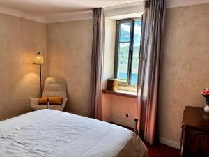 a bedroom with a bed and a chair and a window at Vue Lac avec Terrasse Privée - "Lani" - Ola Verdon in Bauduen