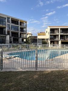 a fence around a swimming pool in front of some apartments at Superbe studio terrasse piscine et plage in Fréjus