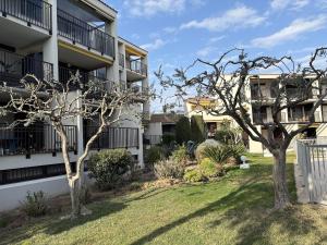 a yard with two trees in front of a building at Superbe studio terrasse piscine et plage in Fréjus