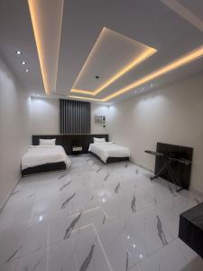 a bedroom with two beds and a large white tile floor at درة القيم in Taif