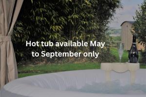 a bottle of wine and a glass on a table at Shepherds hut with hot tub in Bodmin