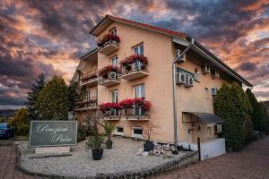 a building with flowers on the balconies and a sign at Penzión Pulse in Podhájska