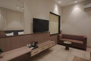 a waiting room with a couch and a flat screen tv at Damru in Jaipur