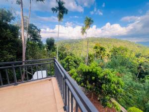 a balcony with palm trees and a hill in the background at Emerald Leaf Kandy Villa in Panabokka