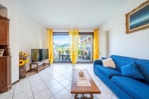 a living room with a blue couch and a tv at Casa Ester a due passi dal lago in Germignaga