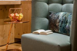 a couch with an open book and a bowl of apples at "Quality Hosts Arlberg" Hotel zur Pfeffermühle in Sankt Anton am Arlberg
