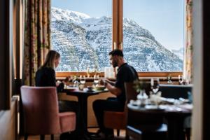 a man and woman sitting at a table in a restaurant at Hotel Goldener Berg in Lech am Arlberg