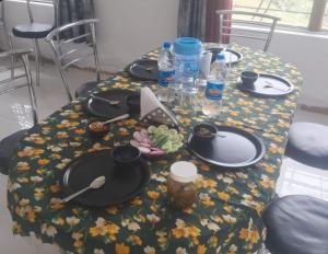 a table with black plates and drinks on a floral table cloth at Omji Niwas - Kalindi in Kharsālī +15 photos
