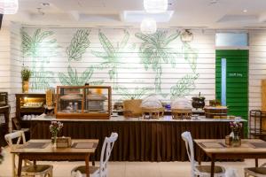 a restaurant with tables and a wall with plants at Brown House Hotel in Udon Thani