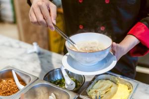 a person is stirring a bowl of food with a spoon at Brown House Hotel in Udon Thani