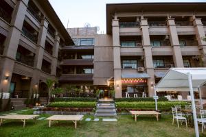 a building with benches and tables in front of it at Brown House Hotel in Udon Thani
