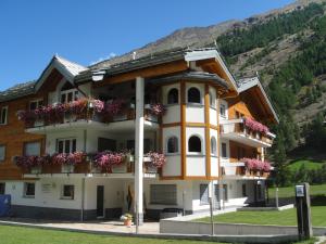 un bâtiment avec des fleurs sur ses balcons dans l'établissement Haus Alpenstern, à Saas-Grund
