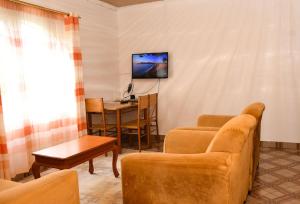 a living room with a couch and a table and a tv at Eldoville Home in Eldoret +2 photos