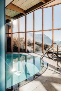 a swimming pool in a building with windows at Hotel Goldener Berg in Lech am Arlberg